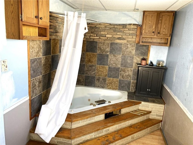 bathroom with a paneled ceiling, hardwood / wood-style floors, and shower / tub combo