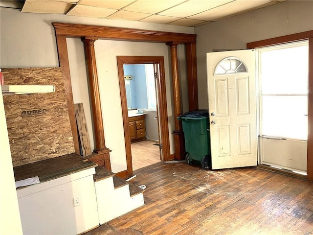 entrance foyer featuring a drop ceiling, dark wood-type flooring, and decorative columns