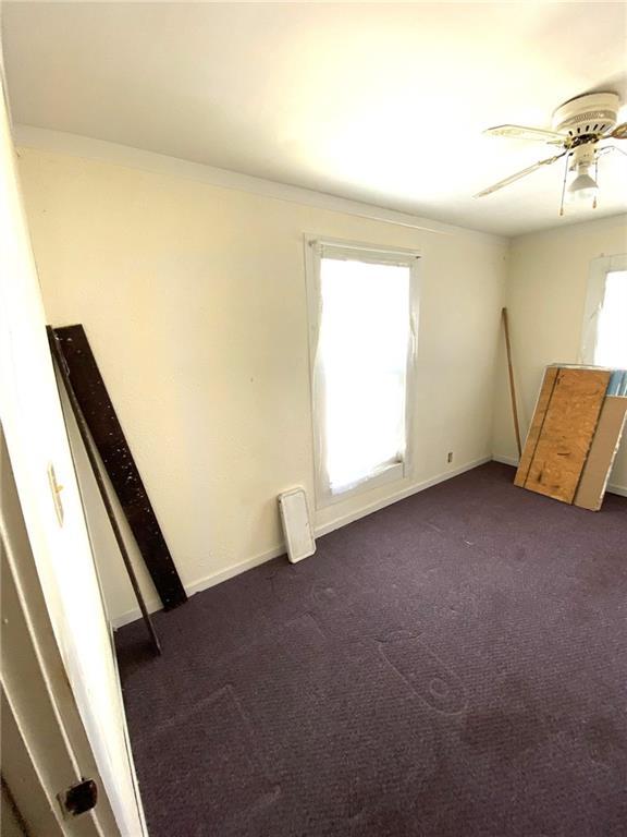 spare room with ceiling fan and dark carpet