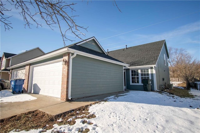 view of snowy exterior featuring a garage and central AC