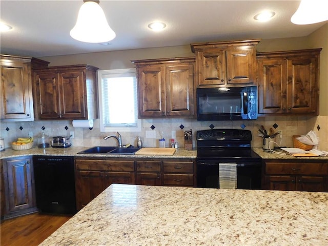 kitchen with tasteful backsplash, decorative light fixtures, sink, and black appliances