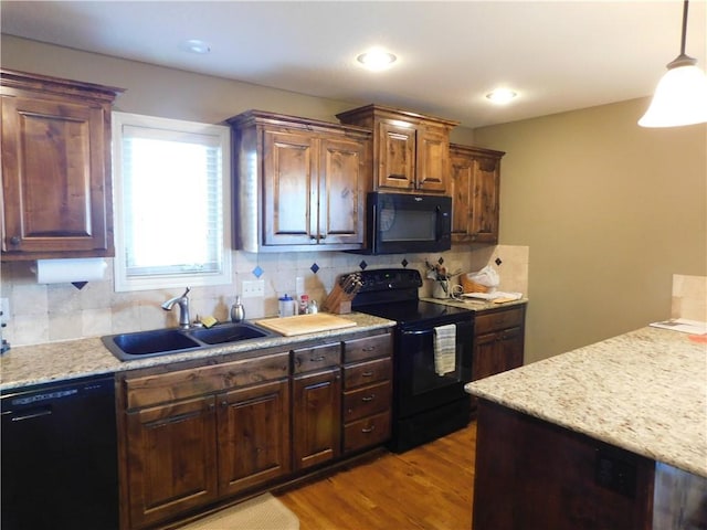 kitchen featuring sink, black appliances, hanging light fixtures, light hardwood / wood-style flooring, and backsplash