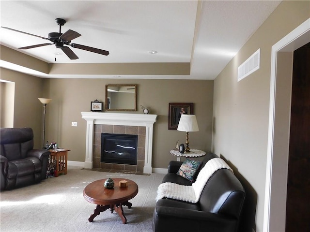 living room with ceiling fan, carpet floors, and a tile fireplace