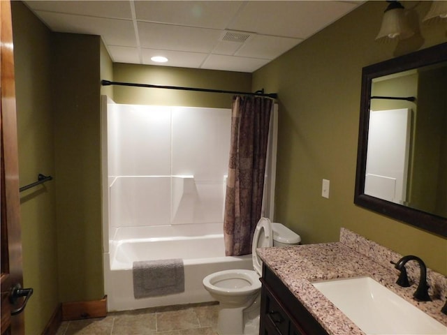 full bathroom featuring vanity, a drop ceiling, shower / tub combo, and toilet