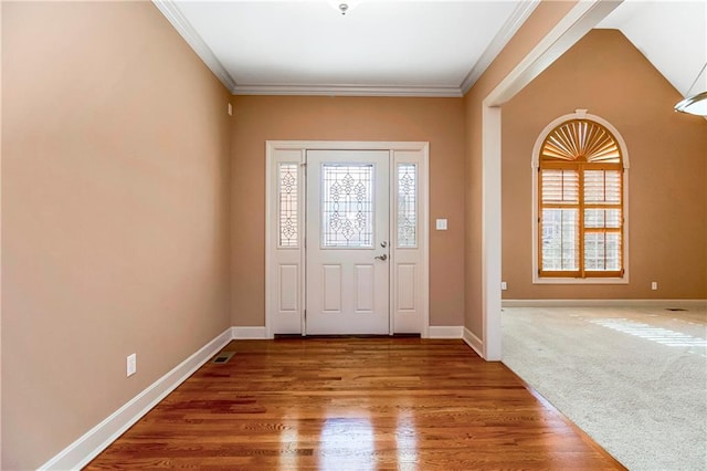 carpeted foyer entrance featuring a wealth of natural light, wood finished floors, and crown molding