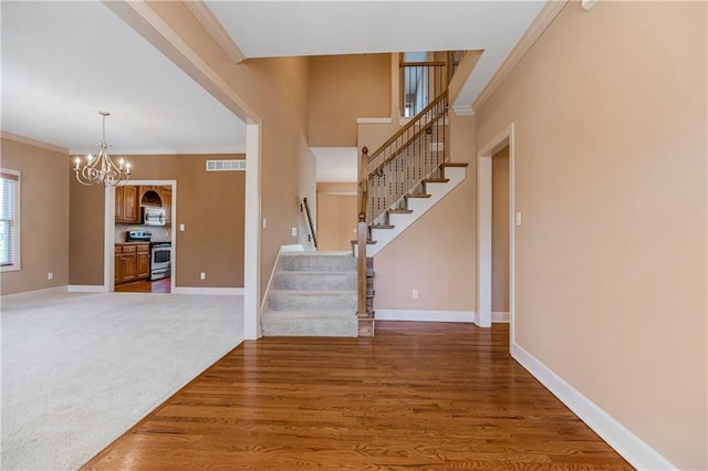 foyer entrance featuring stairs, crown molding, baseboards, and visible vents