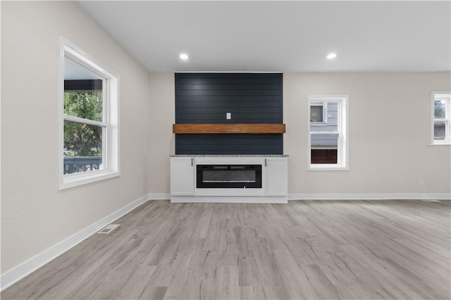 unfurnished living room featuring a healthy amount of sunlight, a fireplace, and light hardwood / wood-style floors