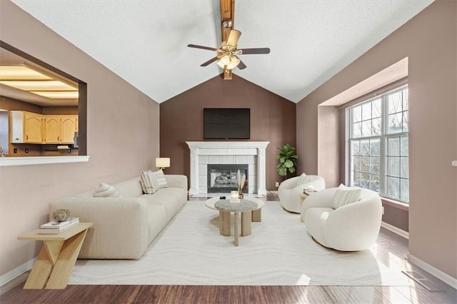 living room featuring lofted ceiling, a tile fireplace, ceiling fan, and light wood-type flooring