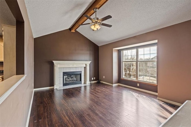 unfurnished living room featuring vaulted ceiling with beams, dark hardwood / wood-style flooring, a tiled fireplace, ceiling fan, and a textured ceiling