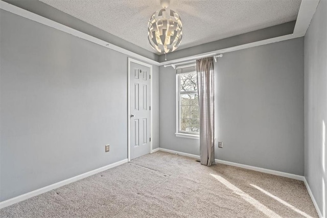 empty room featuring light colored carpet, a chandelier, and a textured ceiling