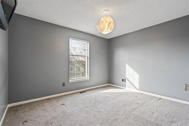 carpeted empty room featuring a textured ceiling