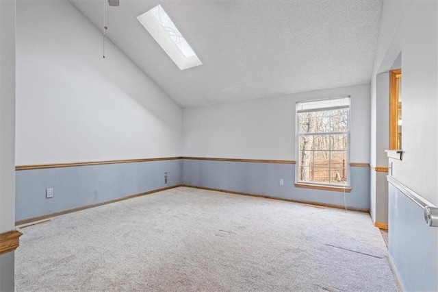 carpeted empty room with lofted ceiling with skylight and a textured ceiling