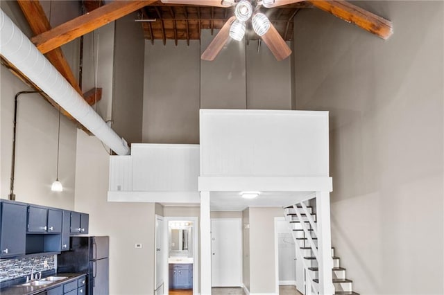 kitchen with blue cabinets, black fridge, tasteful backsplash, ceiling fan, and a high ceiling