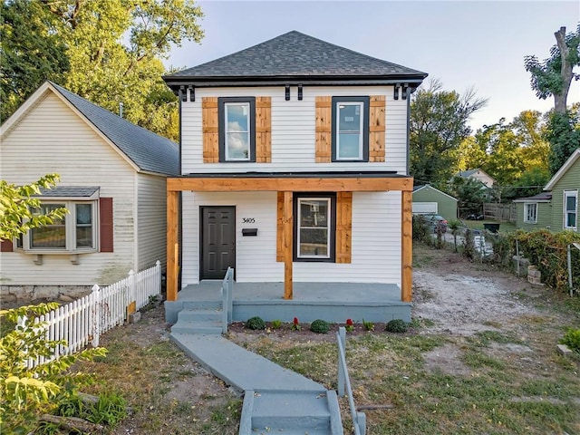 view of front of house with roof with shingles, covered porch, and fence