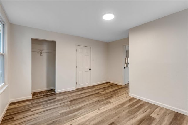 unfurnished bedroom with baseboards, light wood-style flooring, a closet, and multiple windows