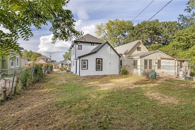 rear view of house with a fenced backyard and a yard
