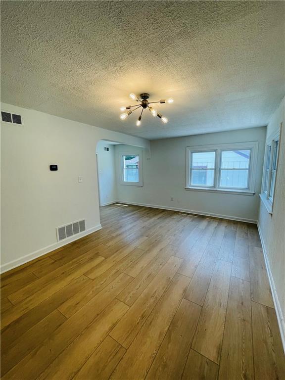 unfurnished room featuring light hardwood / wood-style flooring and a textured ceiling