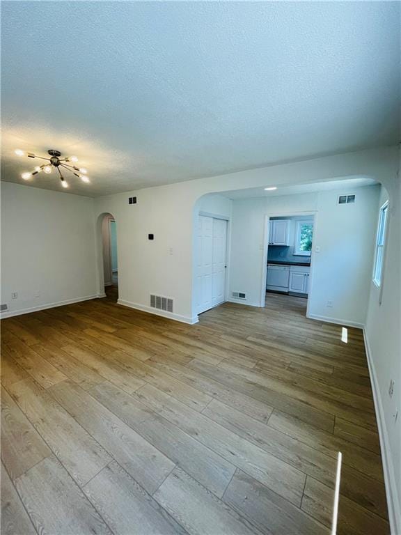 empty room with a textured ceiling and light wood-type flooring