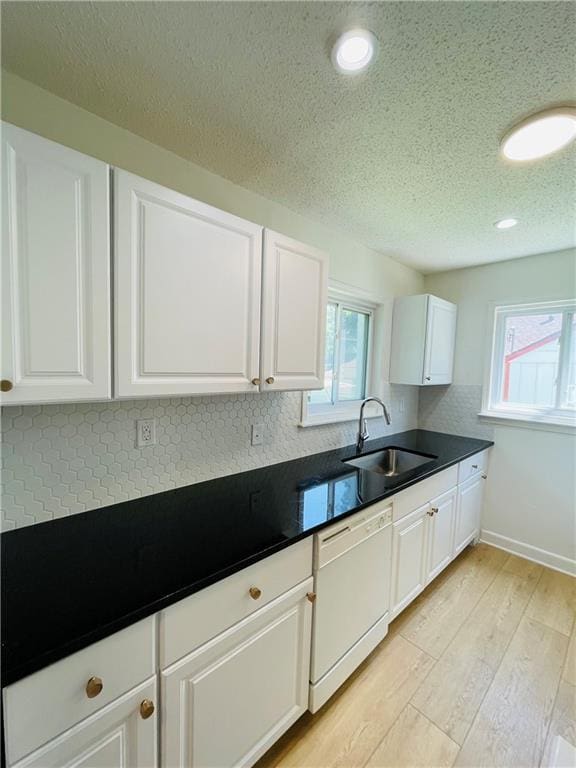 kitchen featuring dishwasher, sink, white cabinets, light hardwood / wood-style floors, and a textured ceiling