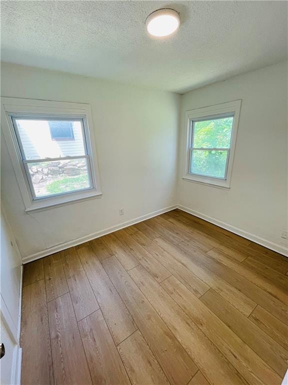 spare room with light hardwood / wood-style floors and a textured ceiling