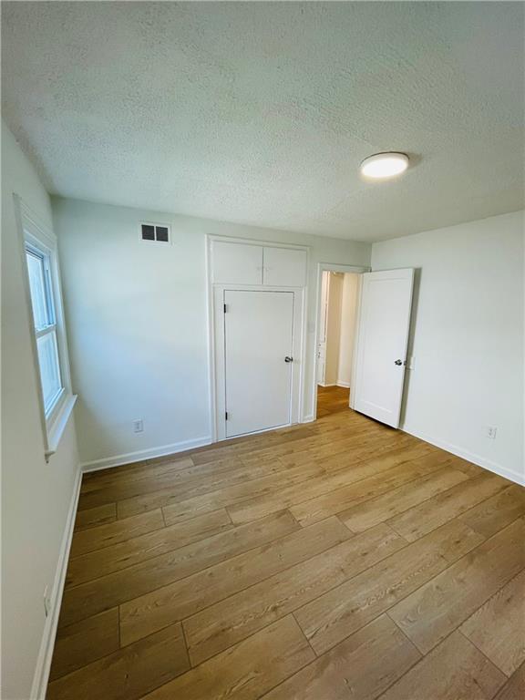 empty room with light hardwood / wood-style flooring and a textured ceiling