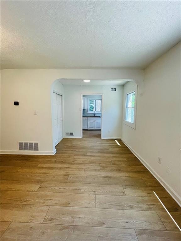 spare room featuring a textured ceiling and light hardwood / wood-style floors