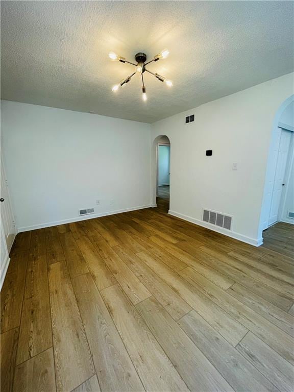 empty room with hardwood / wood-style floors and a textured ceiling