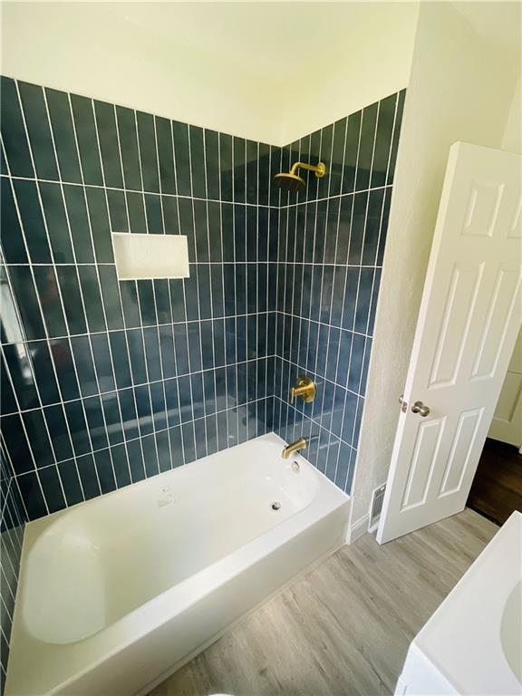 bathroom with tiled shower / bath combo and hardwood / wood-style flooring