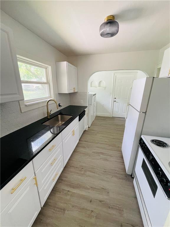 kitchen featuring electric stove, sink, backsplash, light hardwood / wood-style floors, and white cabinets