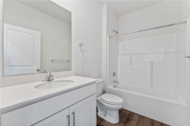 full bathroom with  shower combination, toilet, hardwood / wood-style floors, and vanity