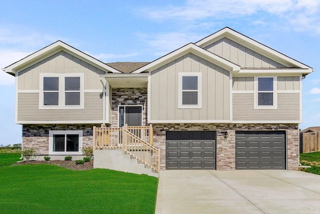 raised ranch featuring an attached garage, stone siding, driveway, board and batten siding, and a front yard