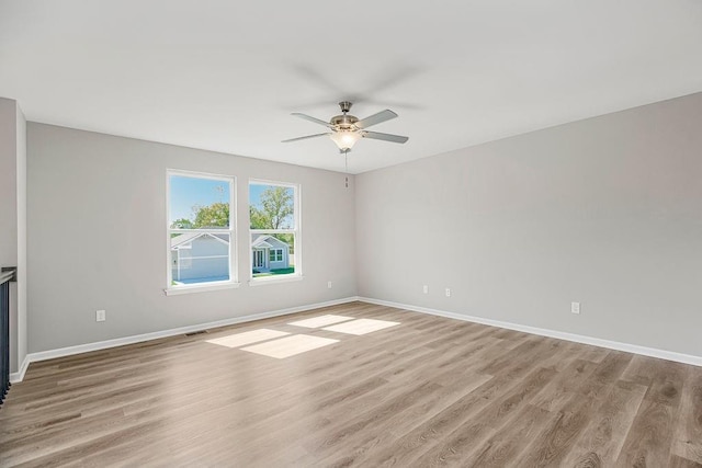 empty room with baseboards, ceiling fan, and light wood-style floors