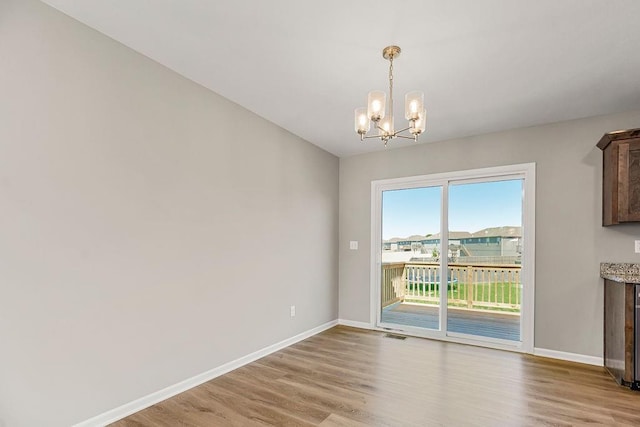 interior space featuring visible vents, a notable chandelier, light wood-style flooring, and baseboards