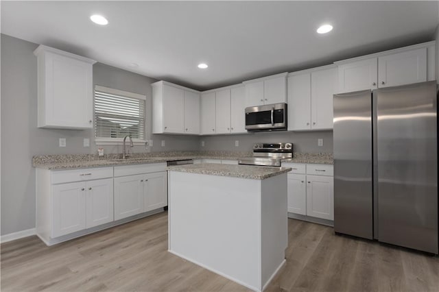 kitchen with stainless steel appliances, a sink, a center island, and white cabinets