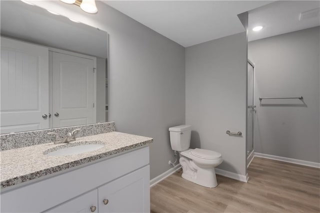 full bathroom with toilet, wood finished floors, vanity, baseboards, and a shower stall