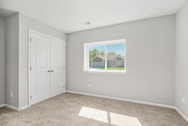 unfurnished bedroom featuring light carpet, baseboards, visible vents, and a closet