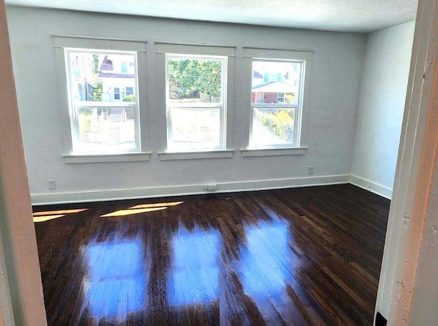 spare room with dark hardwood / wood-style floors and a textured ceiling