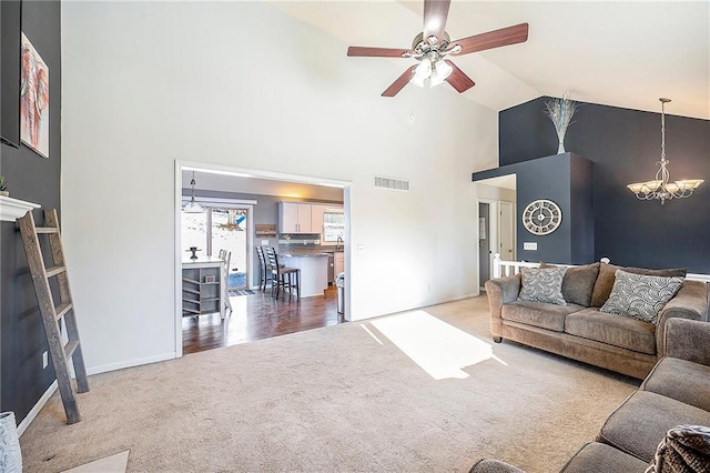 living room with ceiling fan with notable chandelier, high vaulted ceiling, and carpet