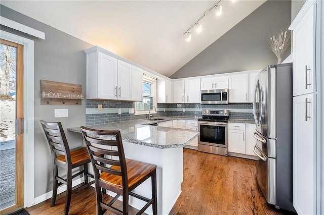 kitchen featuring tasteful backsplash, a breakfast bar area, white cabinets, kitchen peninsula, and stainless steel appliances