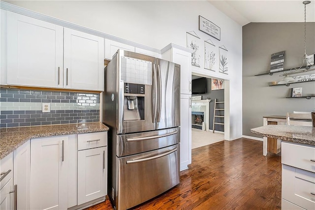 kitchen featuring pendant lighting, white cabinets, backsplash, stainless steel refrigerator with ice dispenser, and light stone countertops