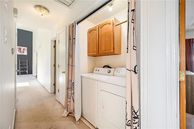 clothes washing area featuring cabinets, washing machine and clothes dryer, and light carpet