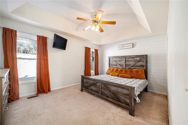 bedroom with multiple windows, ceiling fan, and a tray ceiling