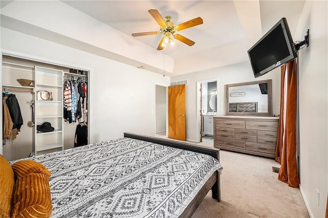 carpeted bedroom with connected bathroom, a tray ceiling, a closet, and ceiling fan