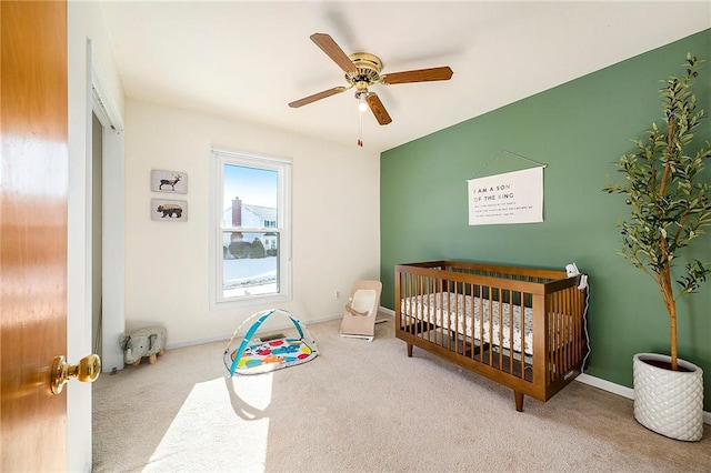 carpeted bedroom with a nursery area and ceiling fan