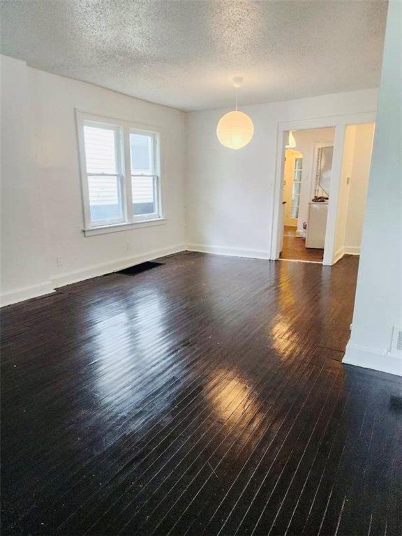 spare room featuring dark hardwood / wood-style floors and a textured ceiling