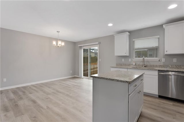 kitchen featuring dishwasher, sink, a kitchen island, and white cabinets