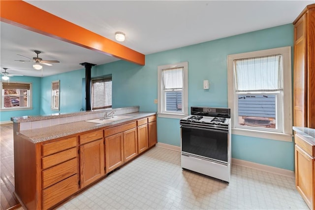 kitchen with kitchen peninsula, sink, gas range gas stove, and a wealth of natural light