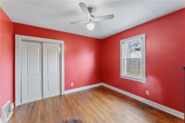 unfurnished bedroom featuring hardwood / wood-style flooring, ceiling fan, and a closet