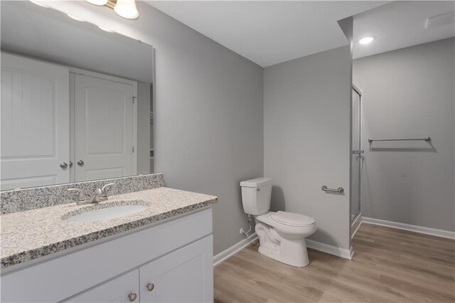 bathroom featuring baseboards, toilet, wood finished floors, vanity, and a shower stall