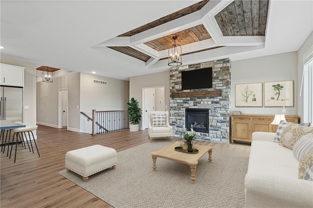 living room featuring a fireplace, visible vents, an inviting chandelier, wood finished floors, and baseboards